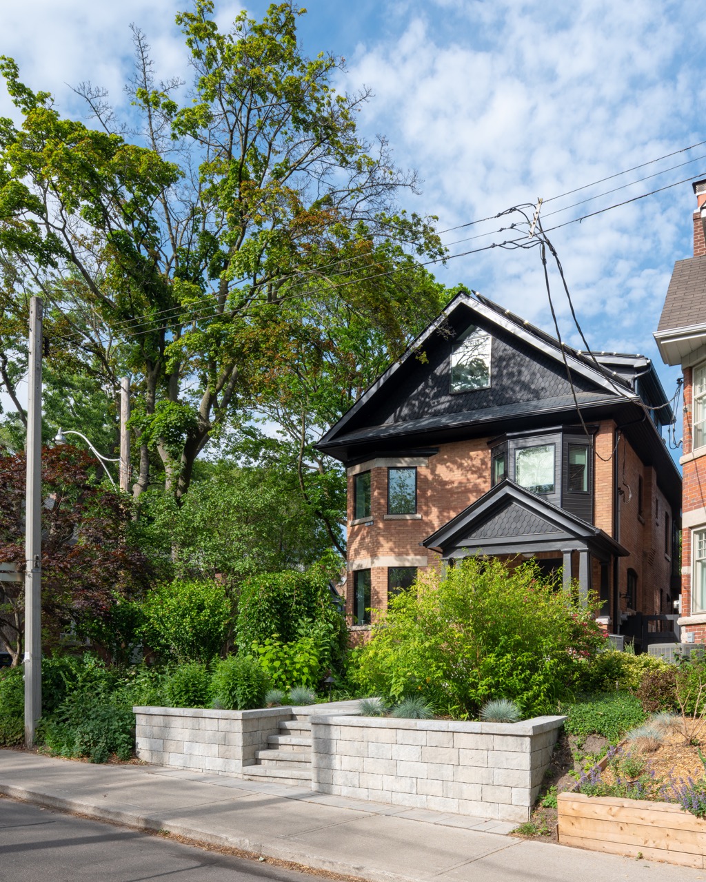 Picturesque Parkside: The exterior kept its dark gabled roofline, wraparound porch, and brick facade intact, while the interior was reimagined around a moody charcoal kitchen with a white oak island, subway tile hood surround, and full-height…