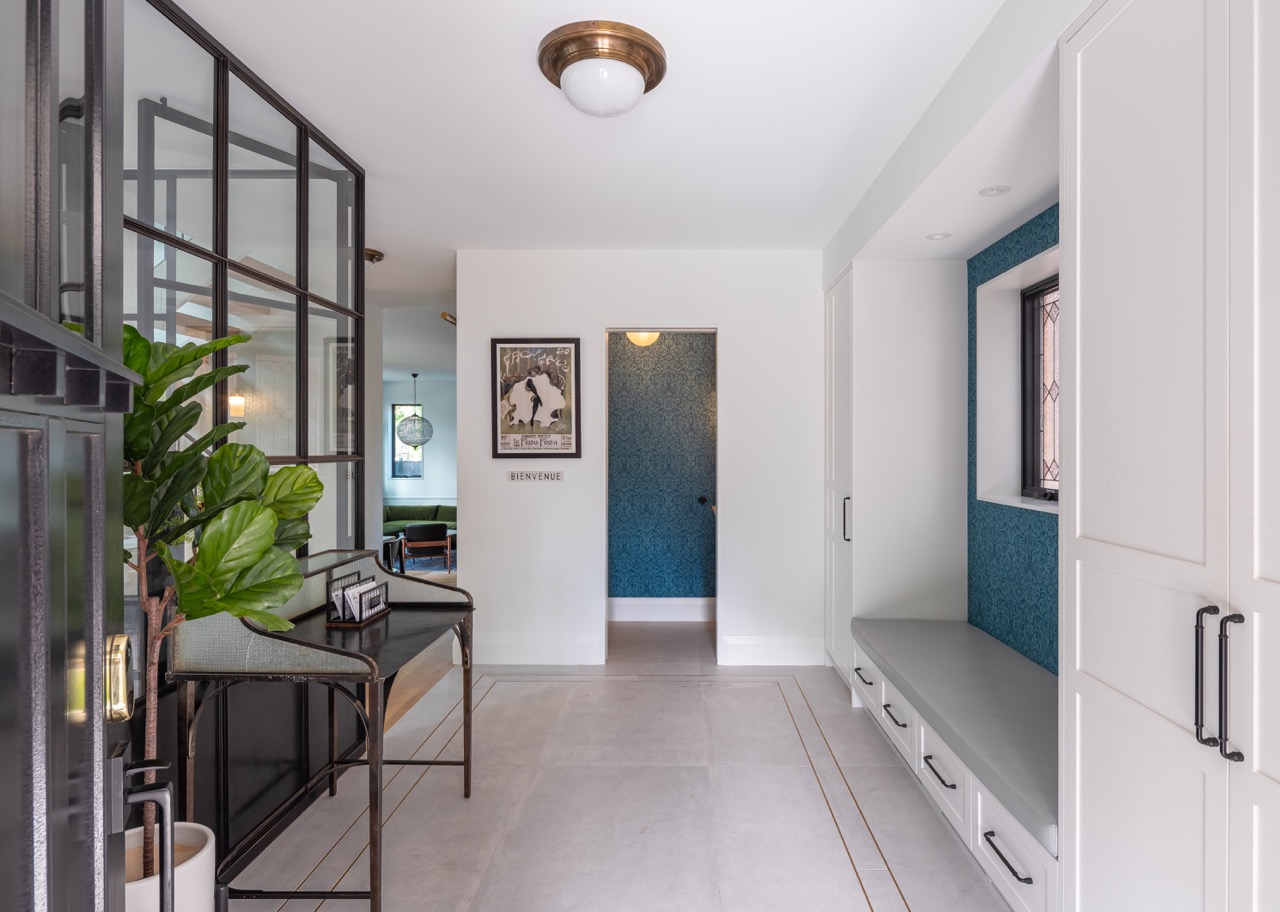 Picturesque Parkside: The exterior kept its dark gabled roofline, wraparound porch, and brick facade intact, while the interior was reimagined around a moody charcoal kitchen with a white oak island, subway tile hood surround, and full-height…