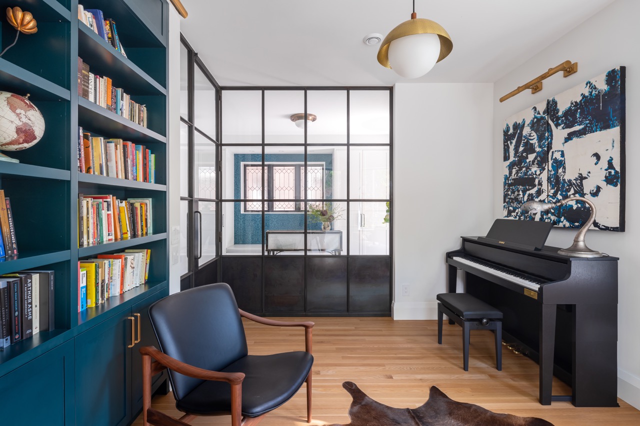 Picturesque Parkside: The exterior kept its dark gabled roofline, wraparound porch, and brick facade intact, while the interior was reimagined around a moody charcoal kitchen with a white oak island, subway tile hood surround, and full-height…