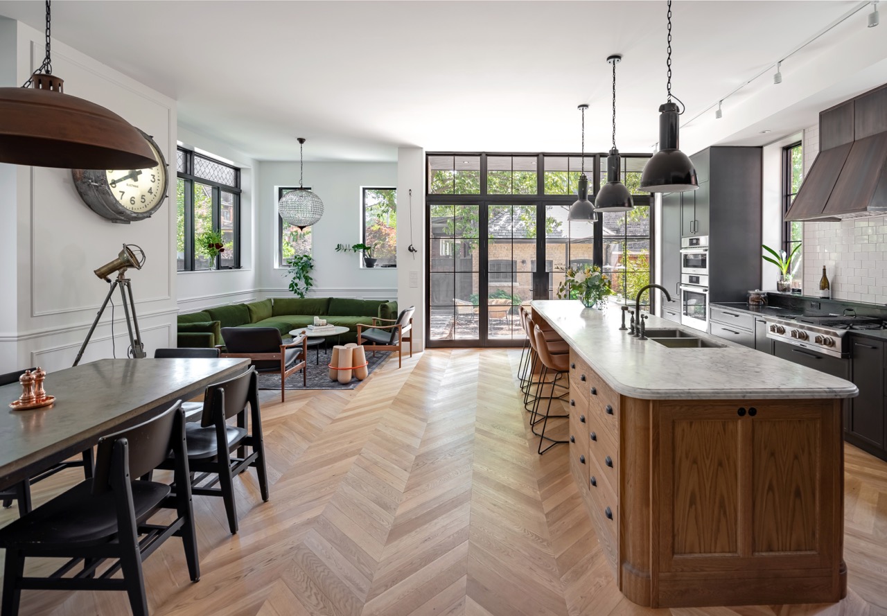 Picturesque Parkside: The exterior kept its dark gabled roofline, wraparound porch, and brick facade intact, while the interior was reimagined around a moody charcoal kitchen with a white oak island, subway tile hood surround, and full-height…
