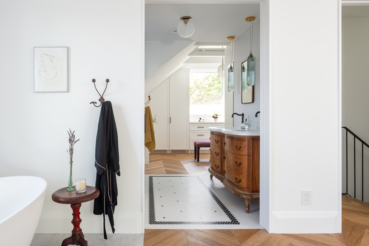 Picturesque Parkside: The exterior kept its dark gabled roofline, wraparound porch, and brick facade intact, while the interior was reimagined around a moody charcoal kitchen with a white oak island, subway tile hood surround, and full-height…