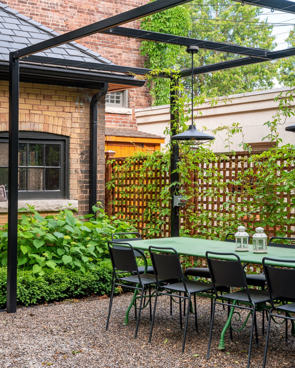 Picturesque Parkside: The exterior kept its dark gabled roofline, wraparound porch, and brick facade intact, while the interior was reimagined around a moody charcoal kitchen with a white oak island, subway tile hood surround, and full-height…