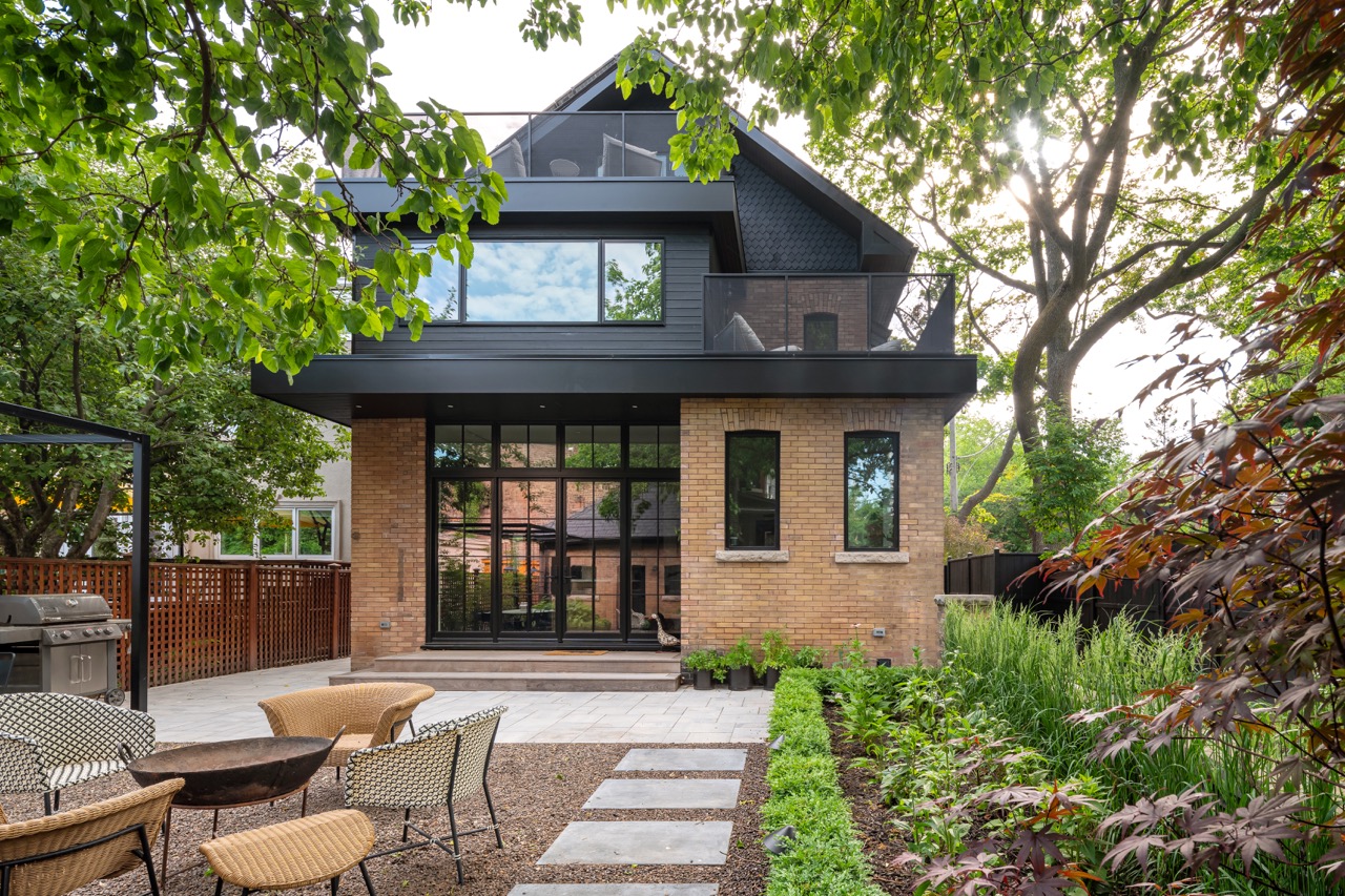Picturesque Parkside: The exterior kept its dark gabled roofline, wraparound porch, and brick facade intact, while the interior was reimagined around a moody charcoal kitchen with a white oak island, subway tile hood surround, and full-height…