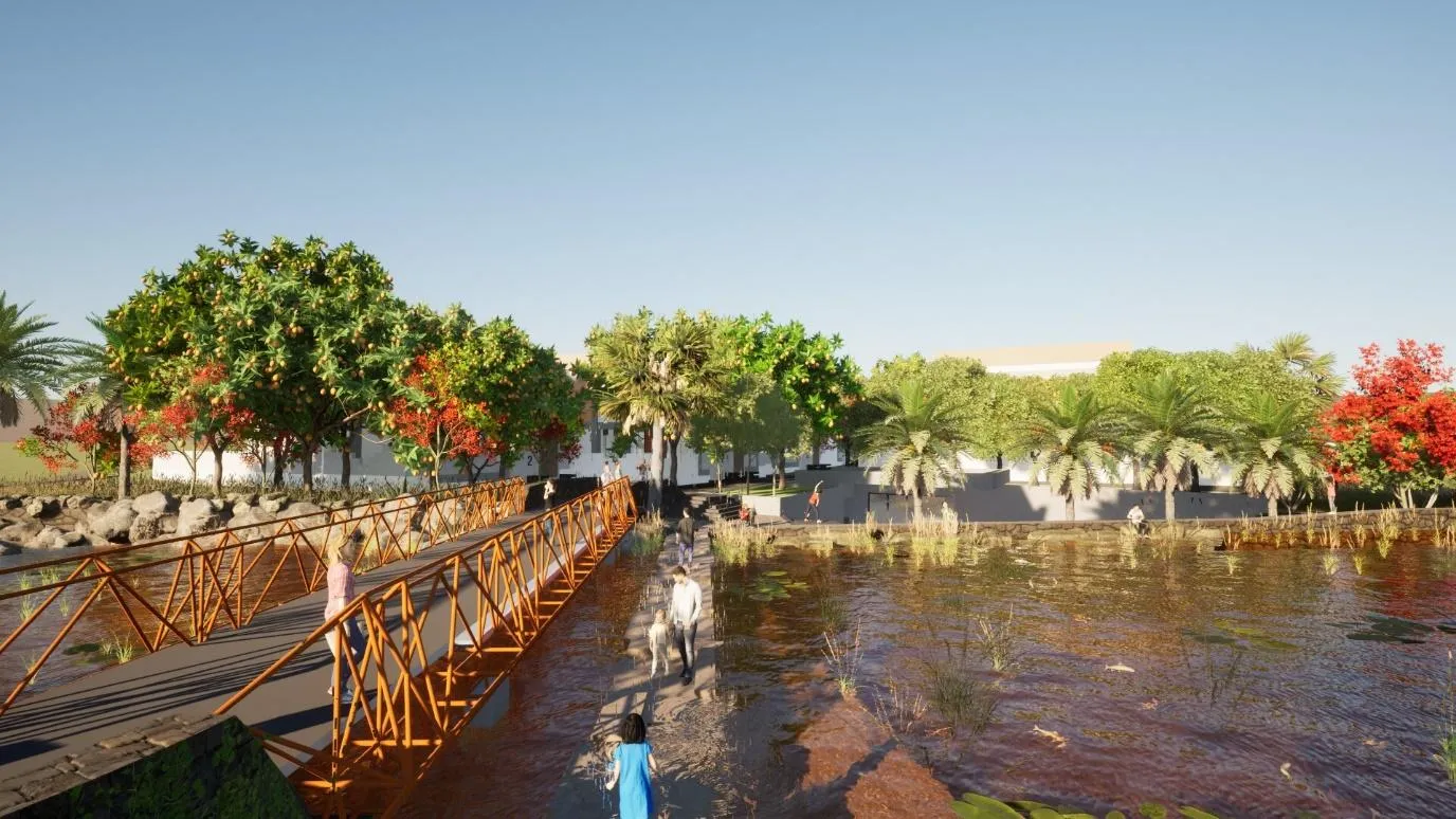 A bridge over a pond with trees and a buildingDescription automatically generated