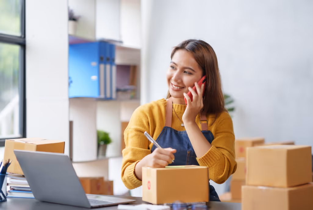 Small business owner packaging boxes at desk representing marketplaces adopting HiHello