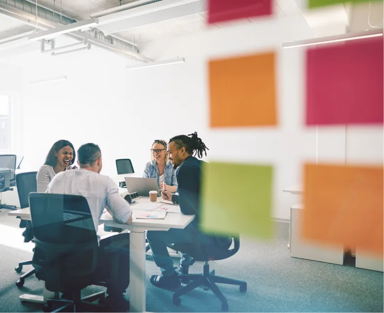 People working in an office setting with post its on a glass wall