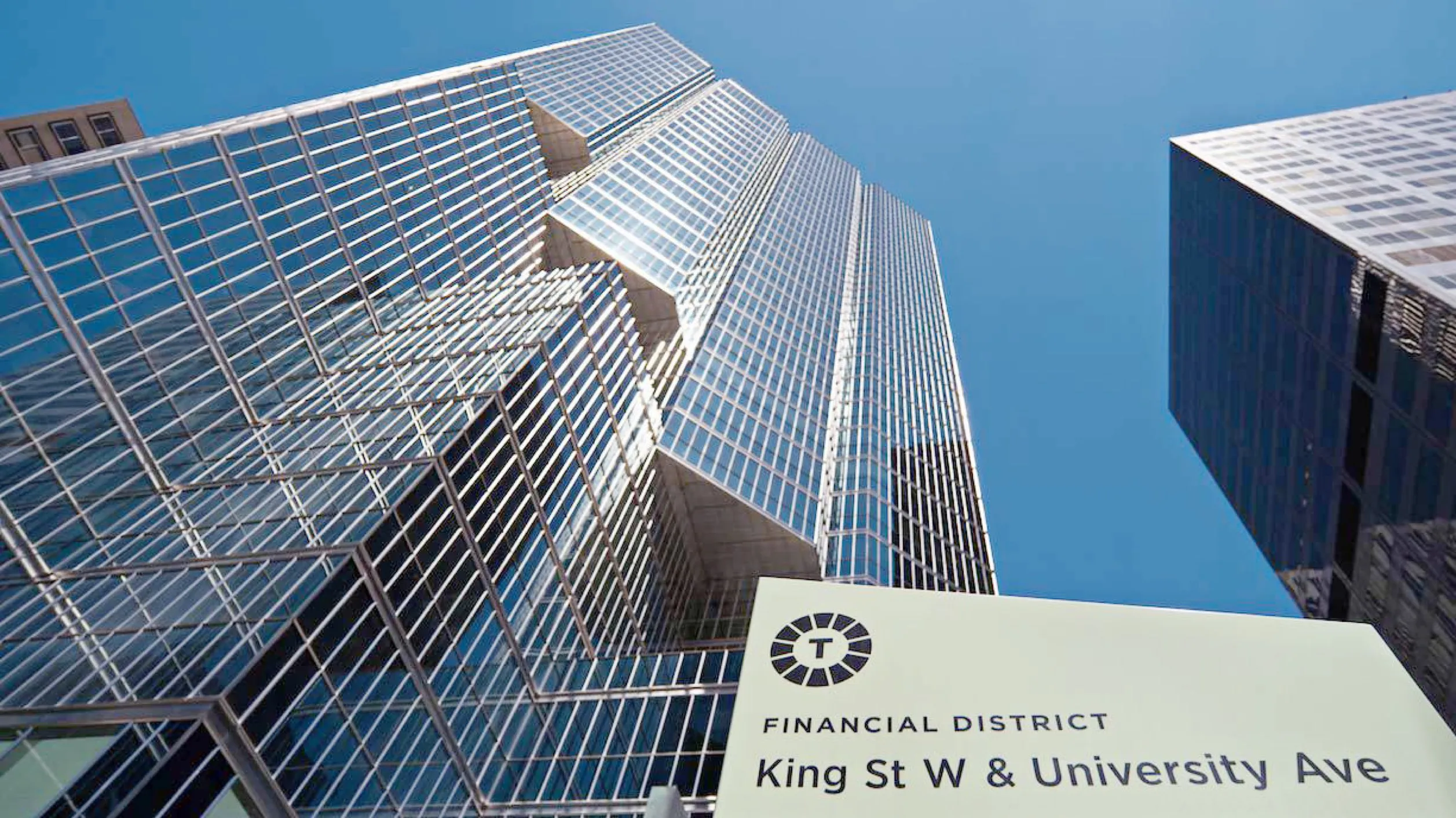 Looking up at tall glass office buildings under a clear blue sky at King St W and University Ave.