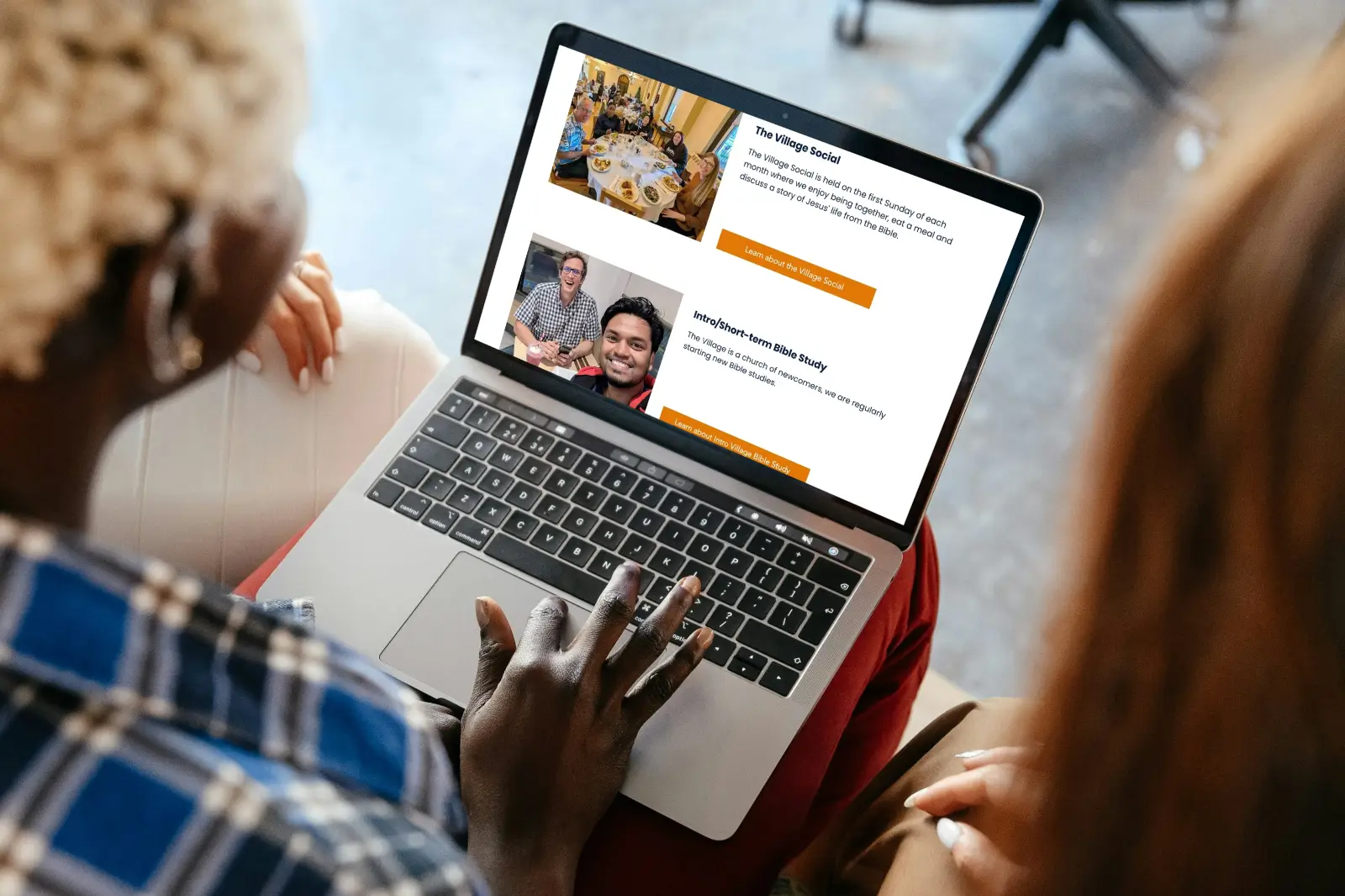 Two people sit closely, viewing a laptop screen showing the community groups section of The Village Church website design.