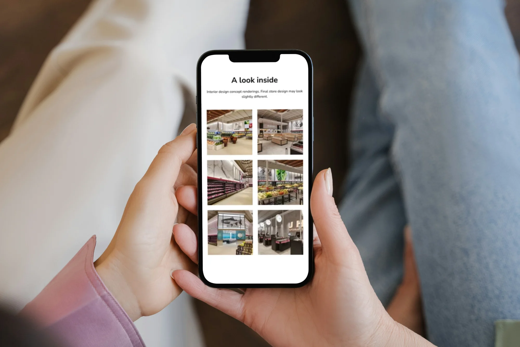 Person holding a smartphone displaying a JH Supermarket's webpage titled 'A look inside' with six small images showing interior design concept renderings of a modern supermarket layout.