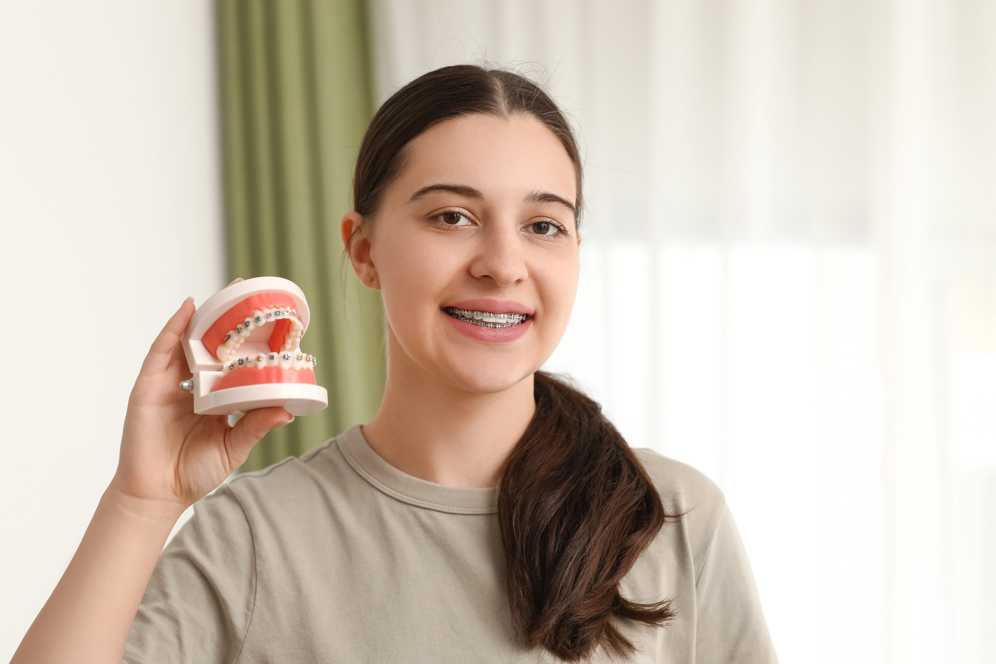 girl holding model of teeth needs orthodontic treatment services