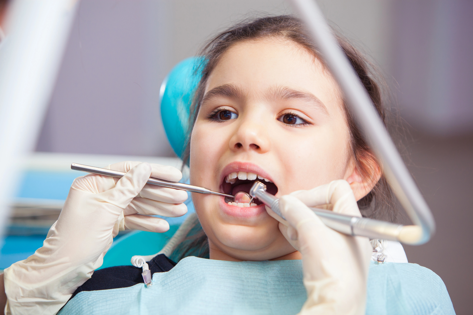 girl getting a dental checkup from a pediatric dentist