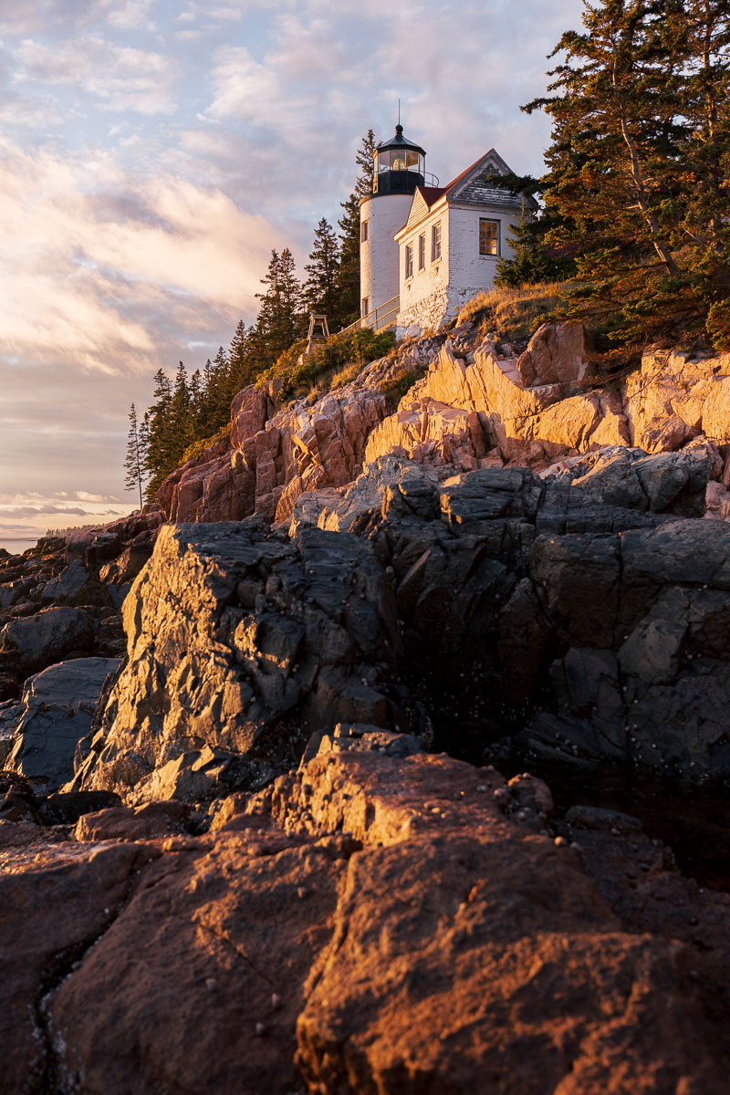 A picturesque lighthouse perched on the edge of a rocky cliff catching golden sunlight in the evening