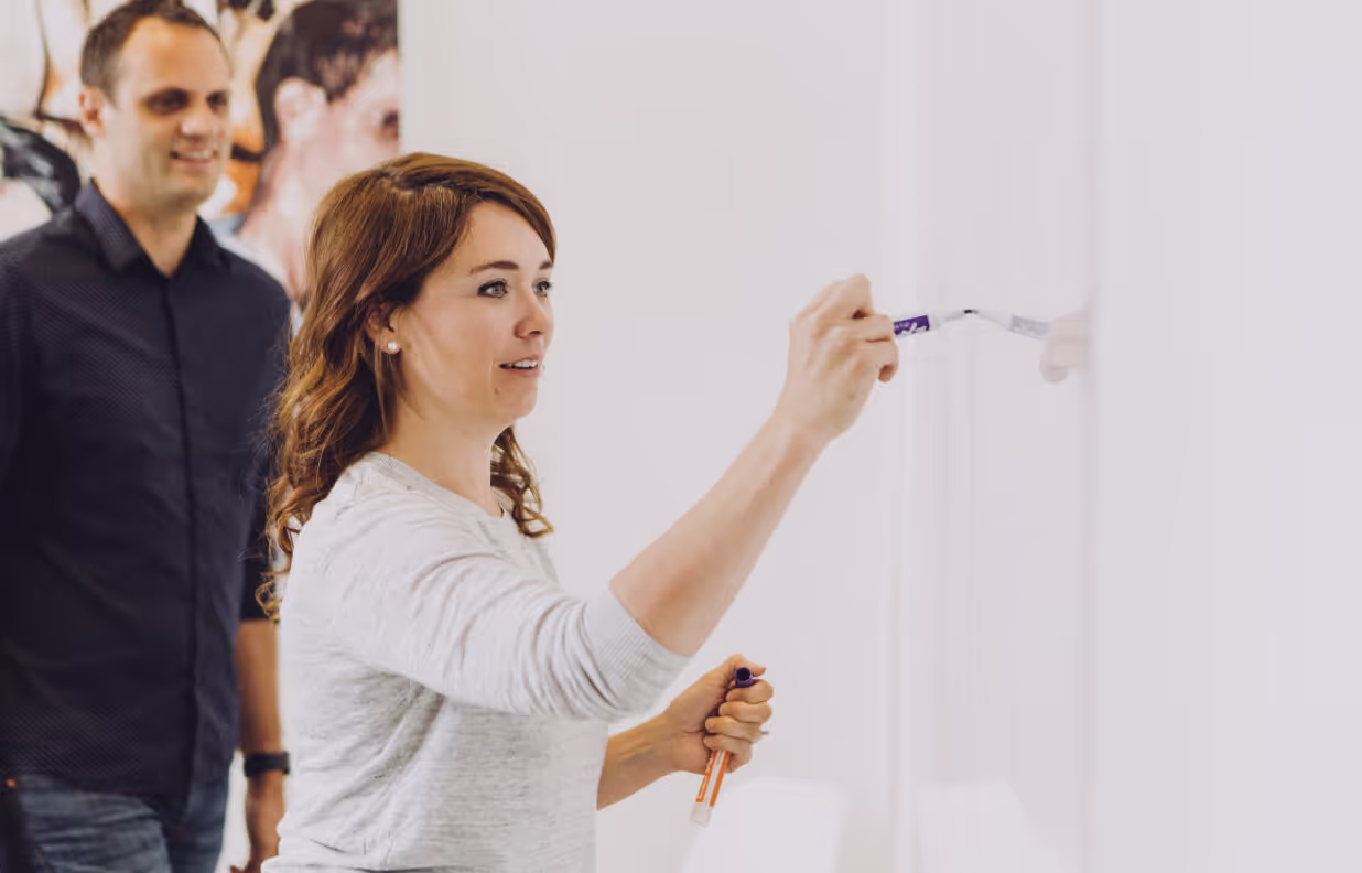 A woman is painting a white wall with a purple marker.