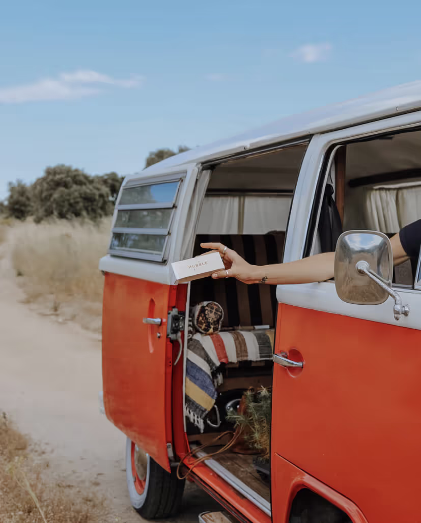 A woman in a red and white van is holding a box.