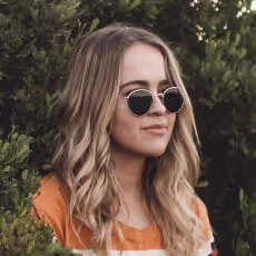A woman with blonde hair wearing sunglasses and an orange shirt.