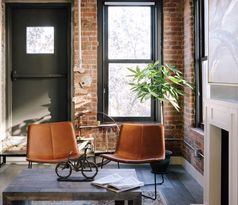 A room with a brick wall and two orange chairs.