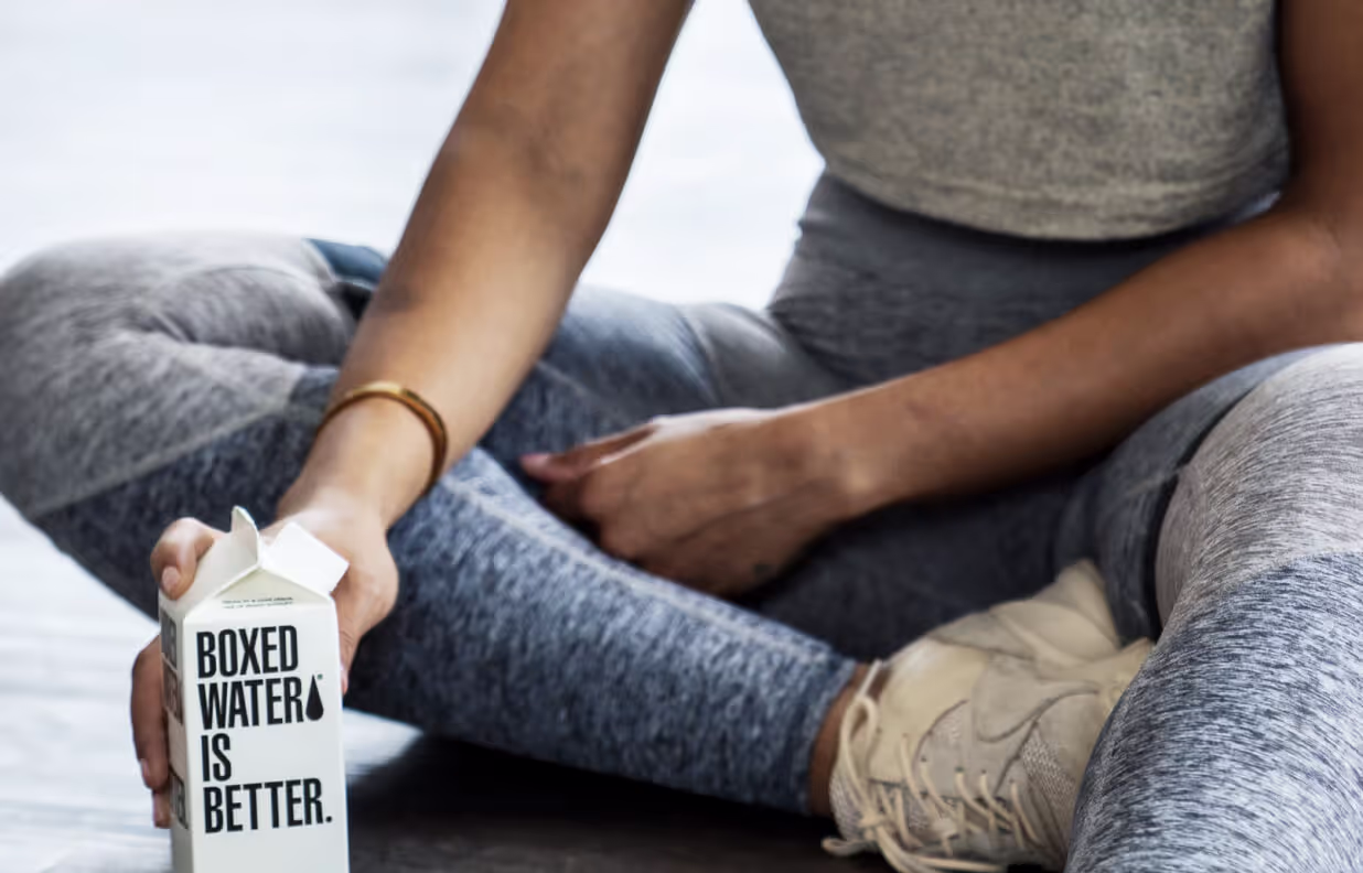 A woman holding a carton of milk with the words "Fresh milk, better water" written on it.