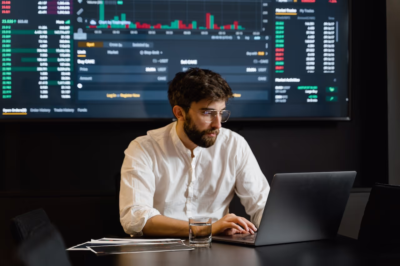 A man wearing glasses and a white shirt is using a laptop helping Dan Beech Wealth Management