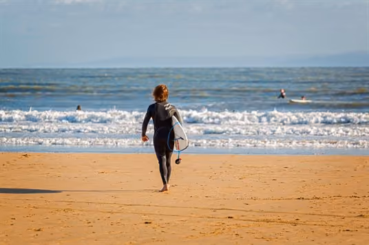 Surfer in wetsuit walking towards the sea