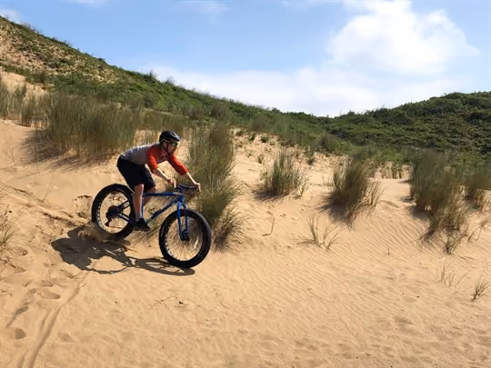 Cyclist riding down sand dune in summer sun
