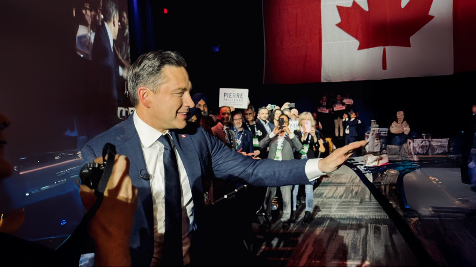 Pierre Polievere in a crowd of people with Canadian flag in the background.