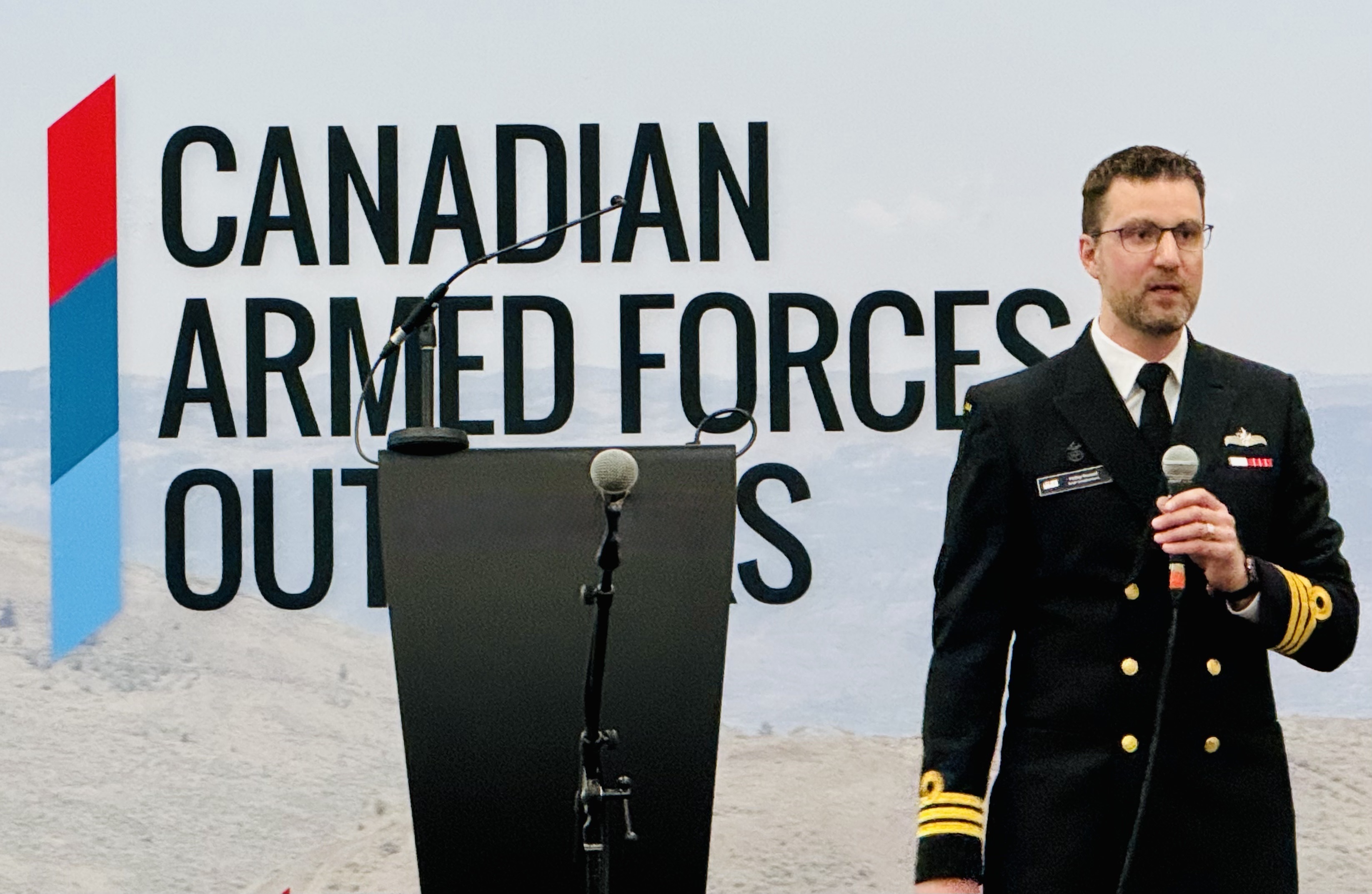 A navy general is standing and speaking at an event near the podium for the Canadian Armed Forces Outlooks.