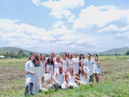 Un grupo de personas en medio de la naturaleza sonríen para la foto. Todos están vestidos de blanco.