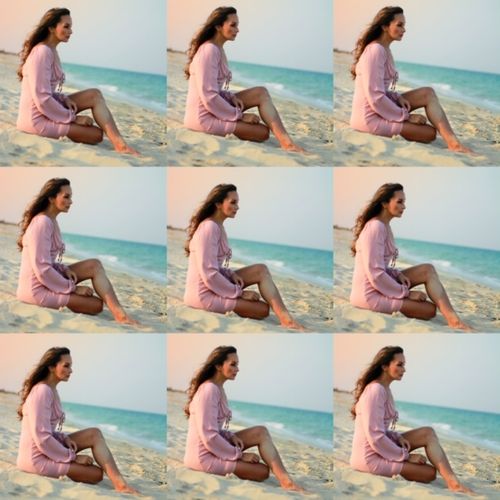 Mujer sentada sobre la arena en frente del mar