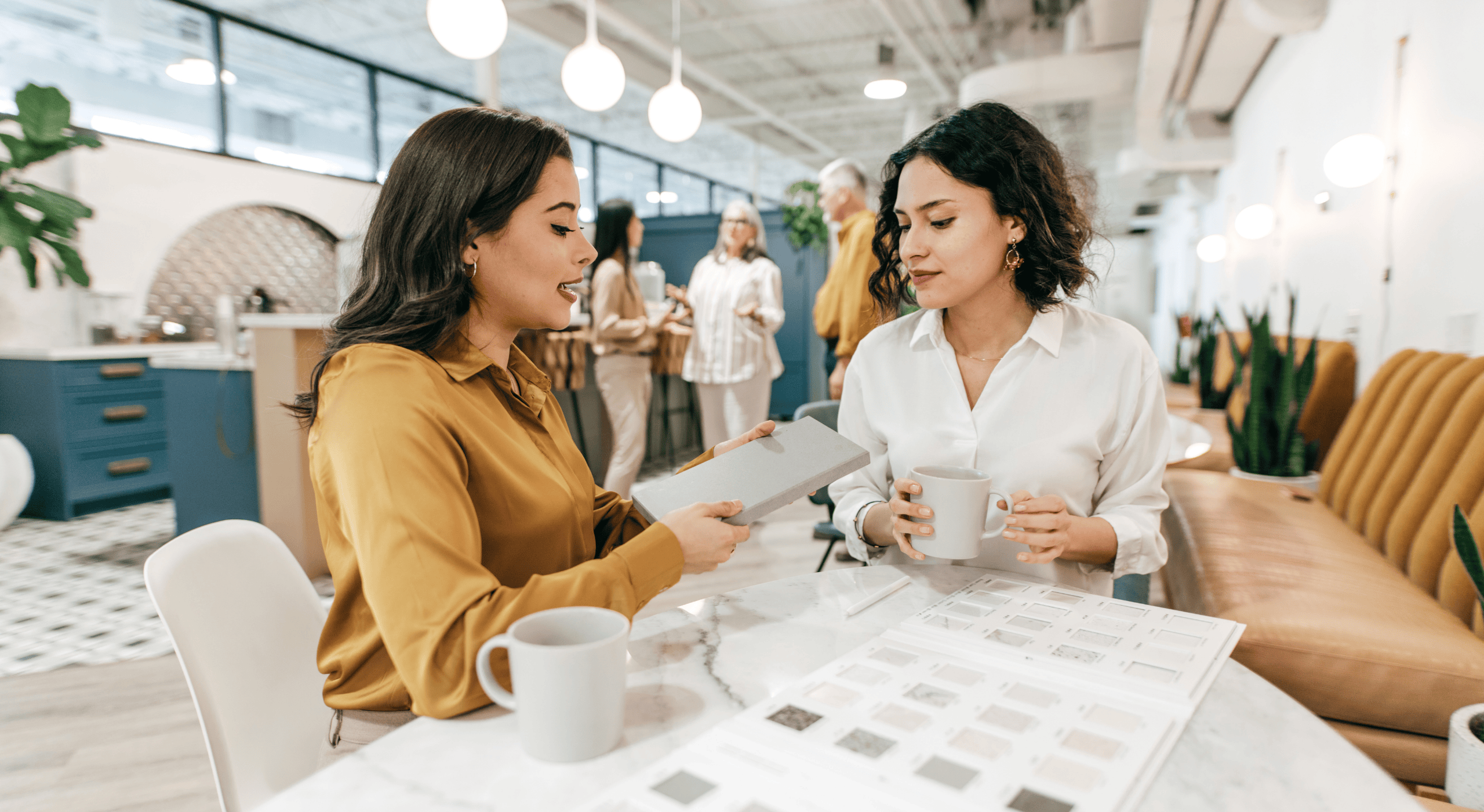 Two women discussing material samples in a modern office, symbolizing career change discussions and planning.