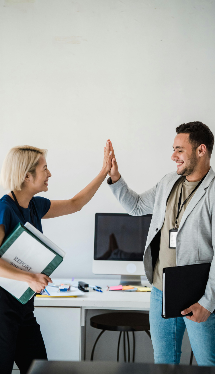 Group of coworkers smiling and high-fiving during a meeting