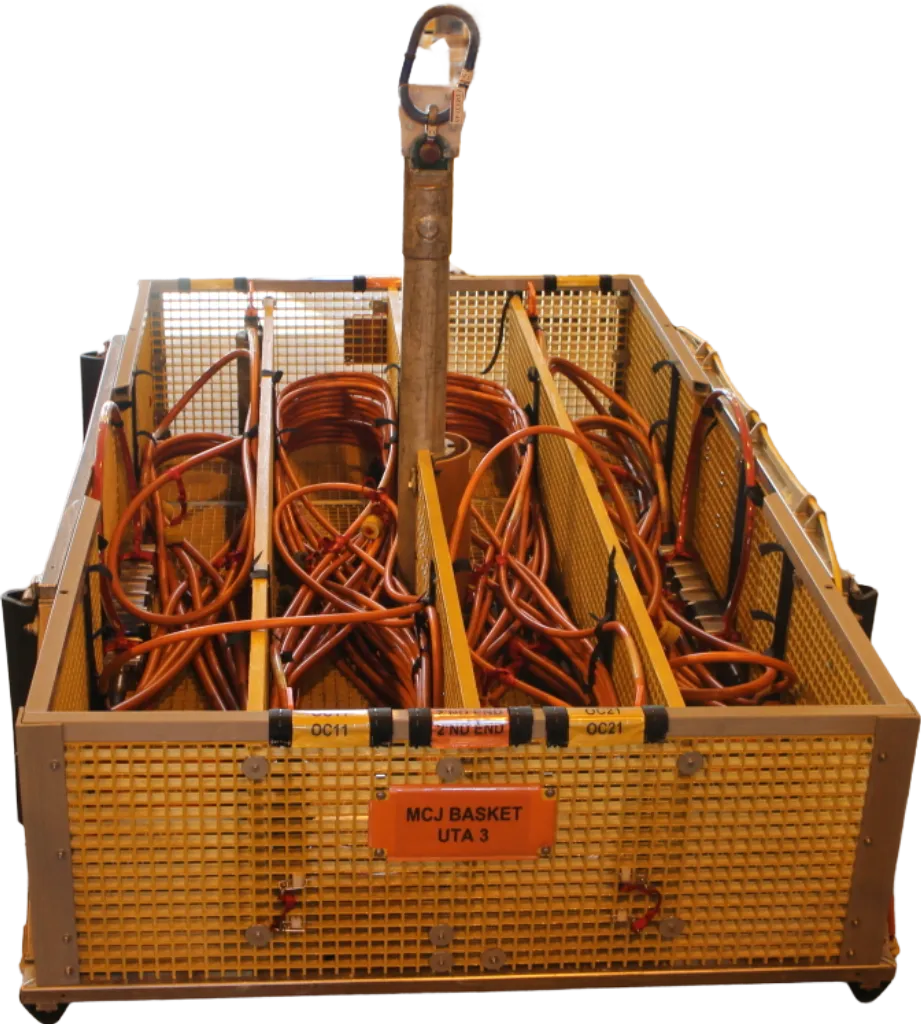Subsea basket UTA 3 with multiple compartments for organized storage of electrical cables, equipped with a lifting hook and cable securing features, in a workshop setting.