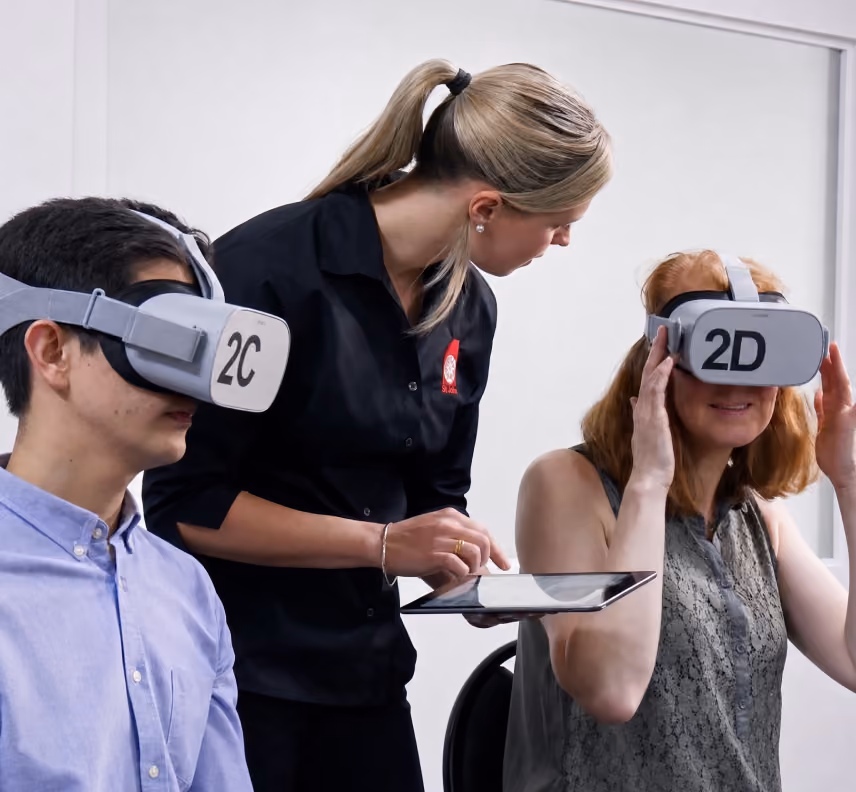 A staff member facilitating two trainees through their VR training modules.