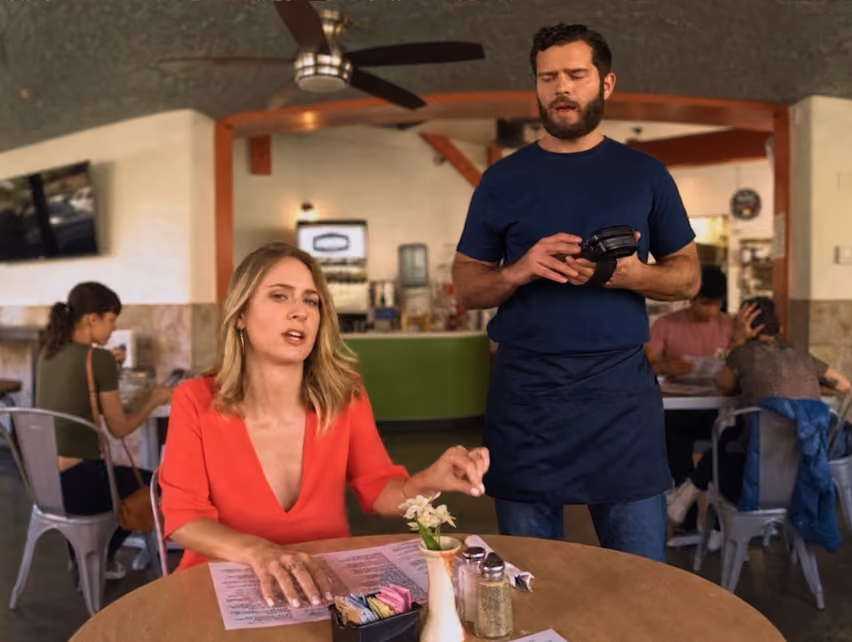 360 degree video showing a live action of VR customer service training in a café scene, with a seated woman customer speaking and a waiter holding a payment device.