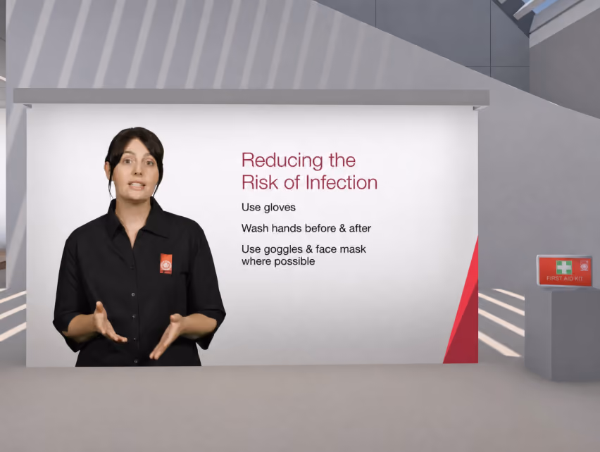 VR training scene of a presenter beside a slide titled "Reducing the Risk of Infection," listing: use gloves, wash hands before and after, use goggles and face mask where possible.