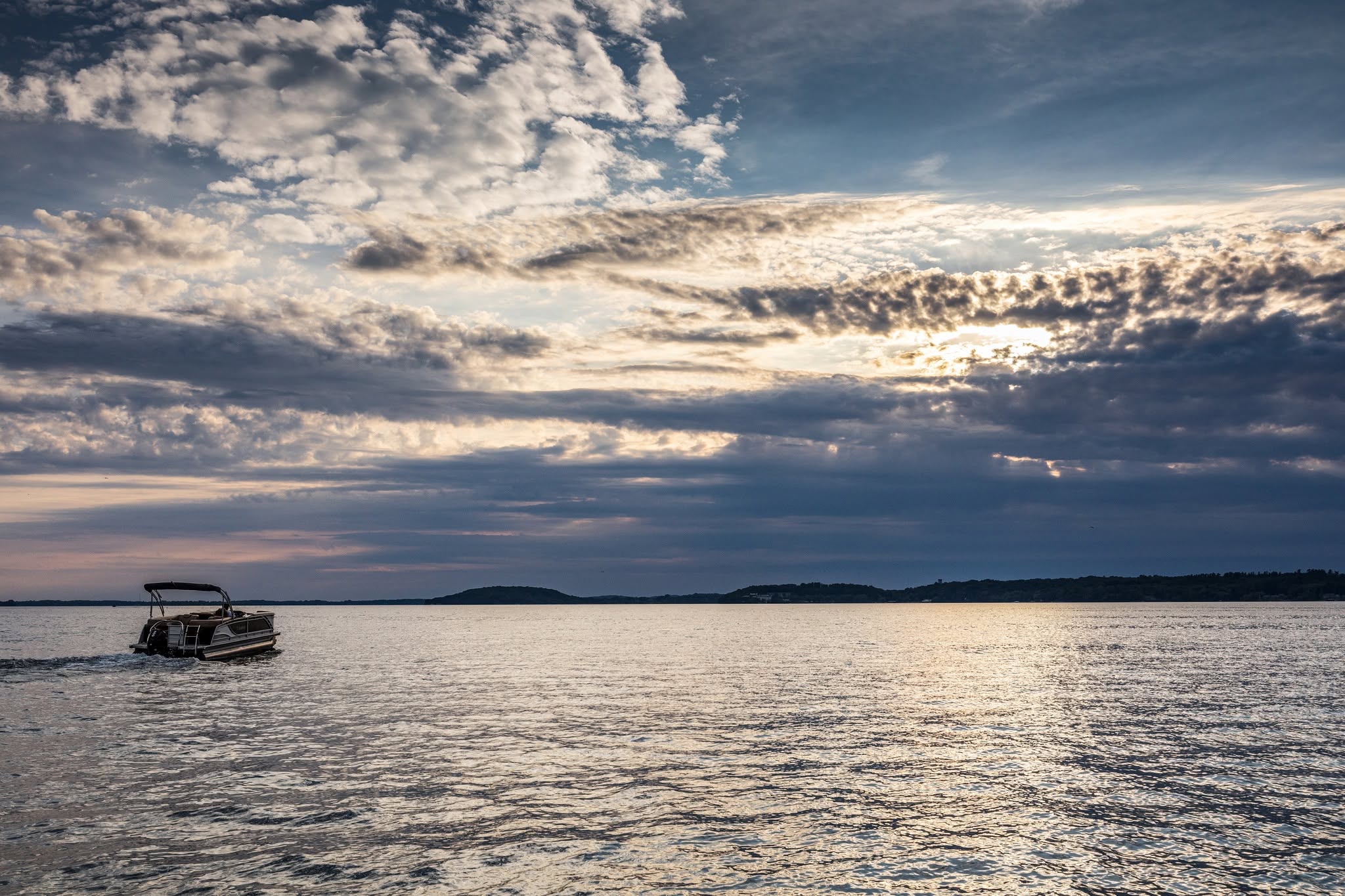 Pontoon boat heading out on Green Lake, Wisconsin, under a dramatic evening sky
