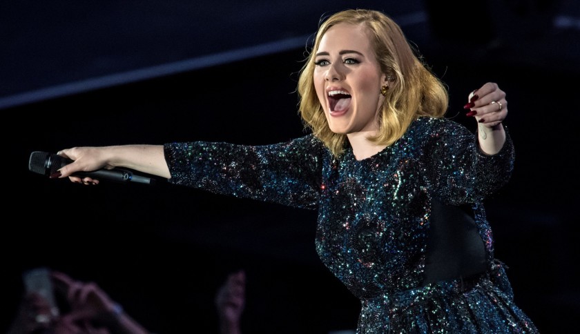 Adele, in concert, is holding out her mic to the audience encouraging her fans to sing with her.