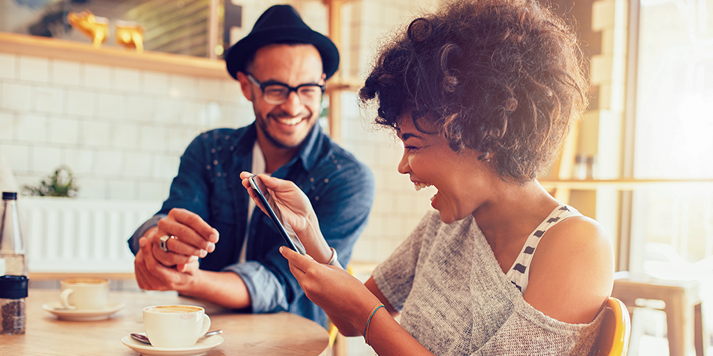 A woman with really short, dark curly hair laughs exuberantly at something on an iPhone. A man sitting beside her laughs along even though he cannot see the screen. When content is written well, with the audience very much in mind, emotions such as this will be evoked as be associated with your brand.