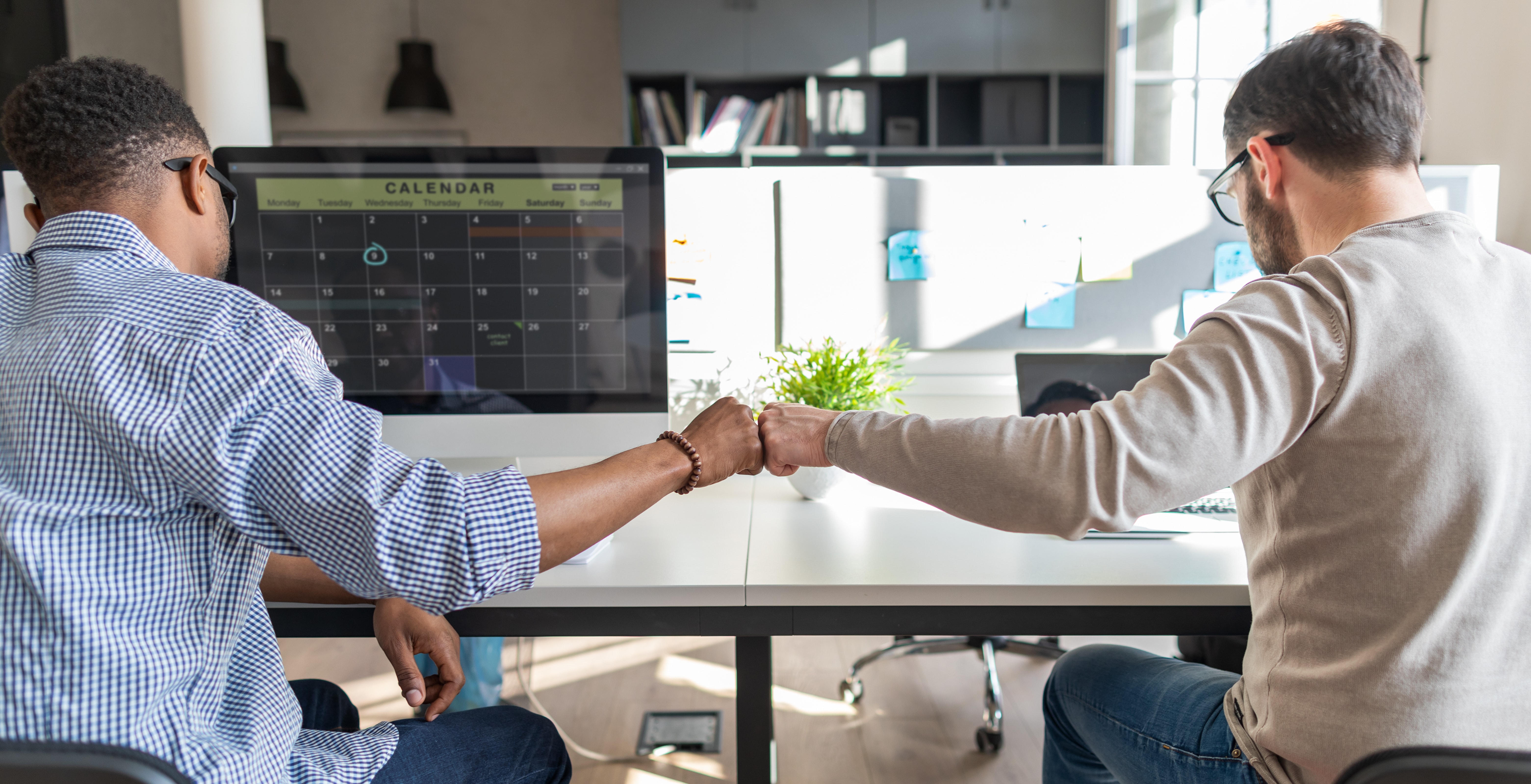 Two men working next to each other fist bumping. They are proud of themselves because their customers think they've their stuff together.