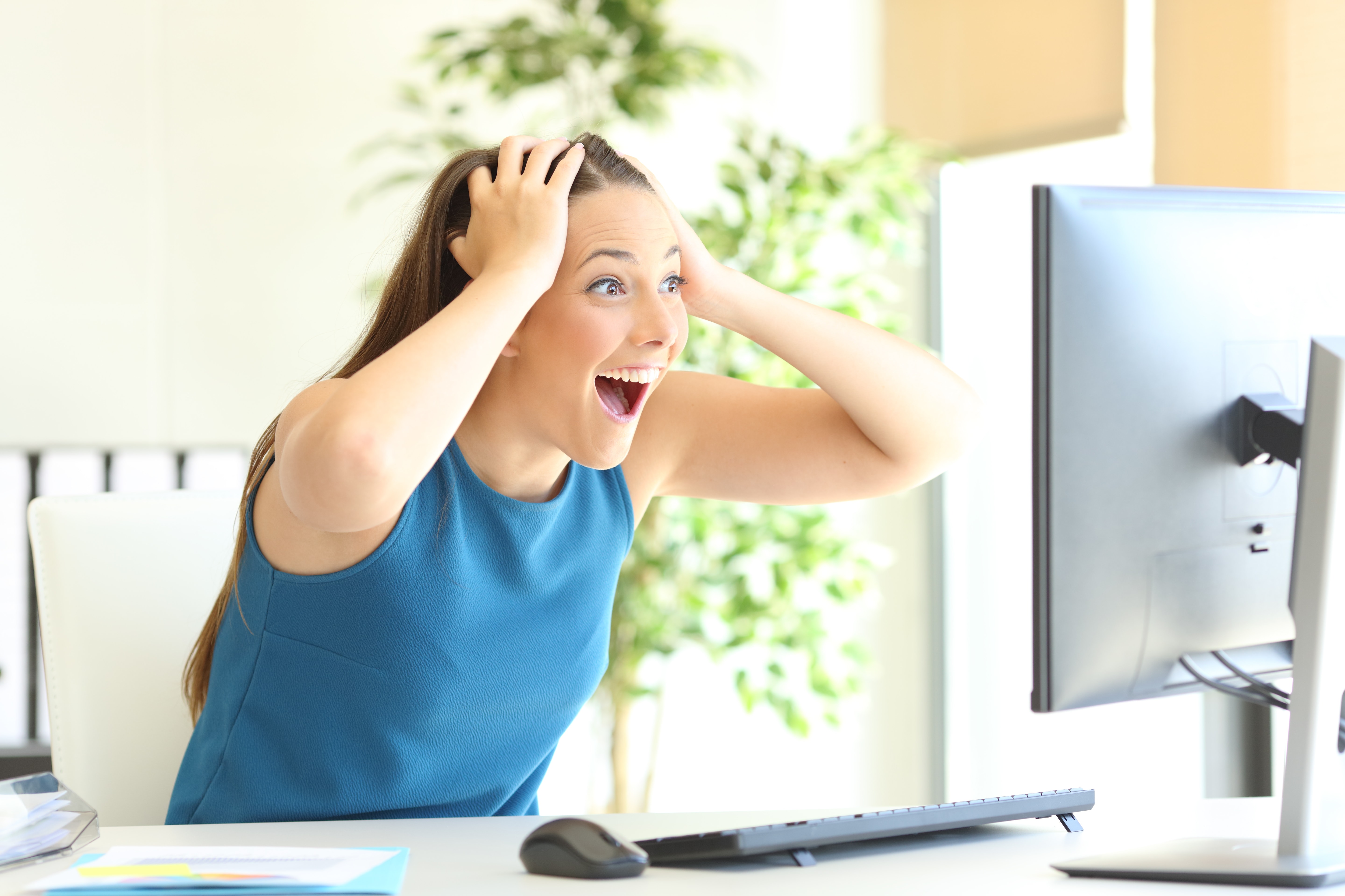 A woman holds her head in her hands, excitedly. She smiles wide at her computer, as if she were in the middle of an excited scream. She leans forward as if she can't believe what she's seeing. Surprising customers can create an emotional connection between you and your customers. Just make sure it's a good one, like this one.