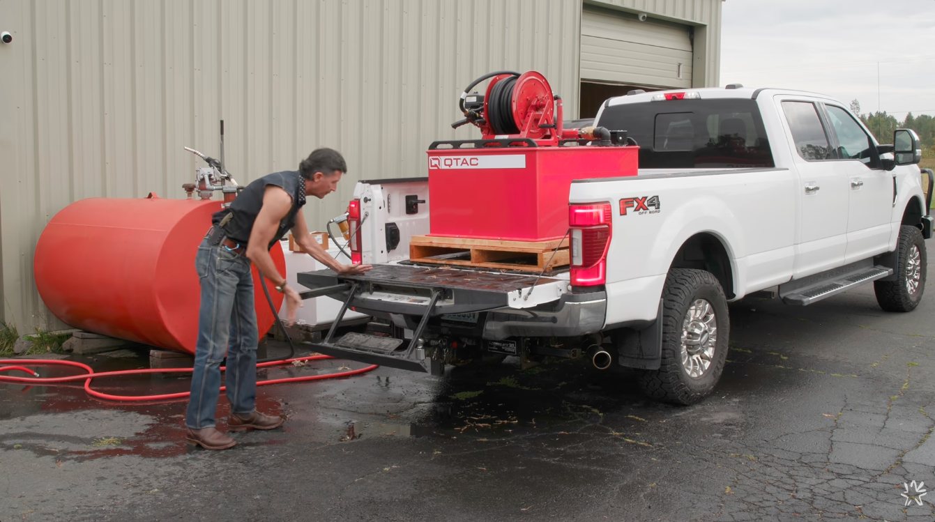 Wranglerstar sliding the QTAC 125HP skid on a pallet from the tailgate into the bed of his crew cab pickup
