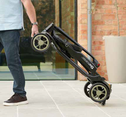 Man rolt een opgevouwen scootmobiel over straat aan het handvat, als een koffer.