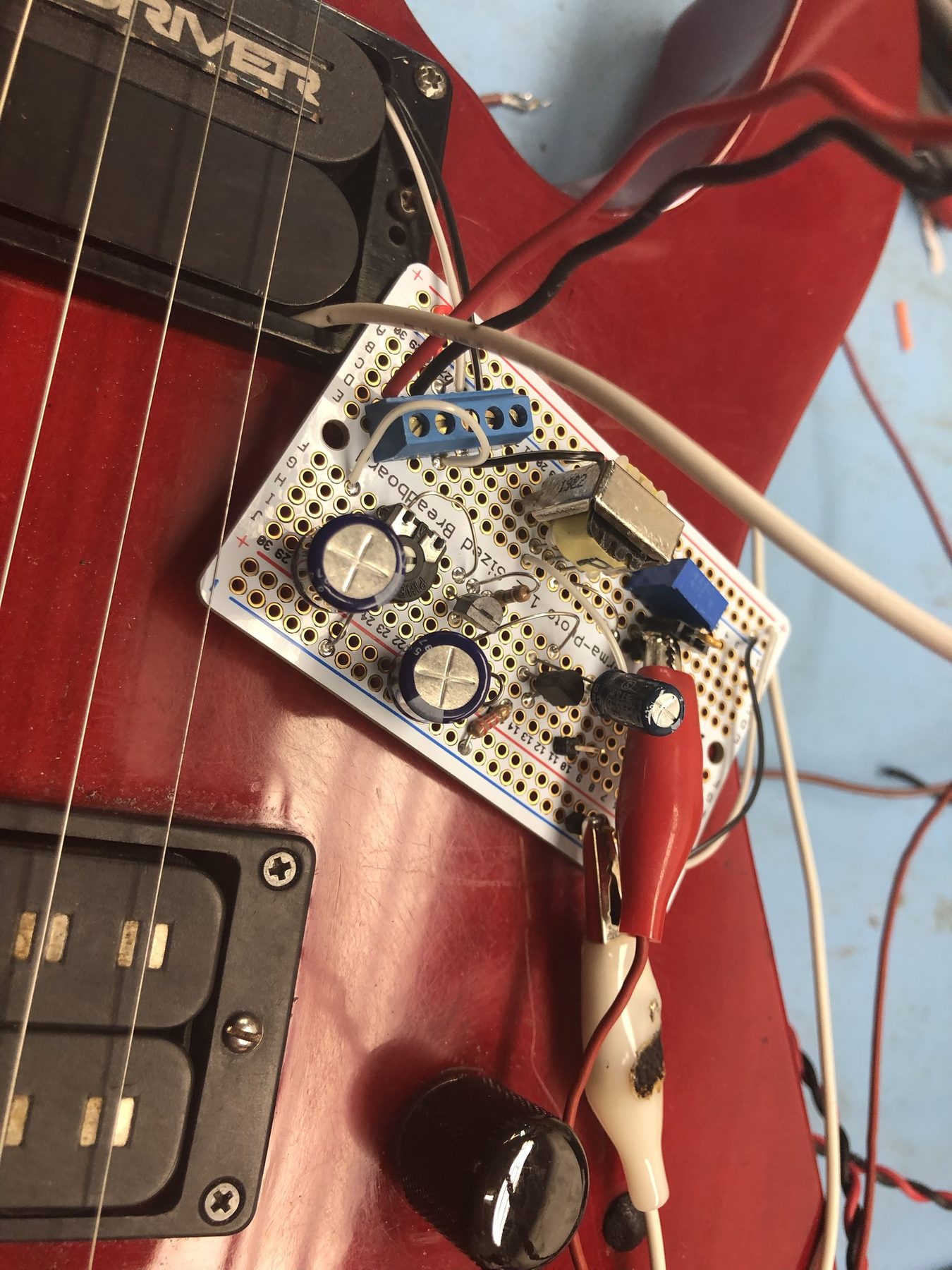 A Hard Driver sustainer driver and prototype circuit board wired into an electric guitar during development testing