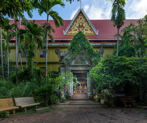 Ornate Khmer pagoda entrance with a red tiered roof and lush greenery in Siem Reap