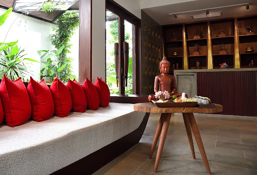 Lounge seating with red cushions and a carved Buddha statue on a wooden table