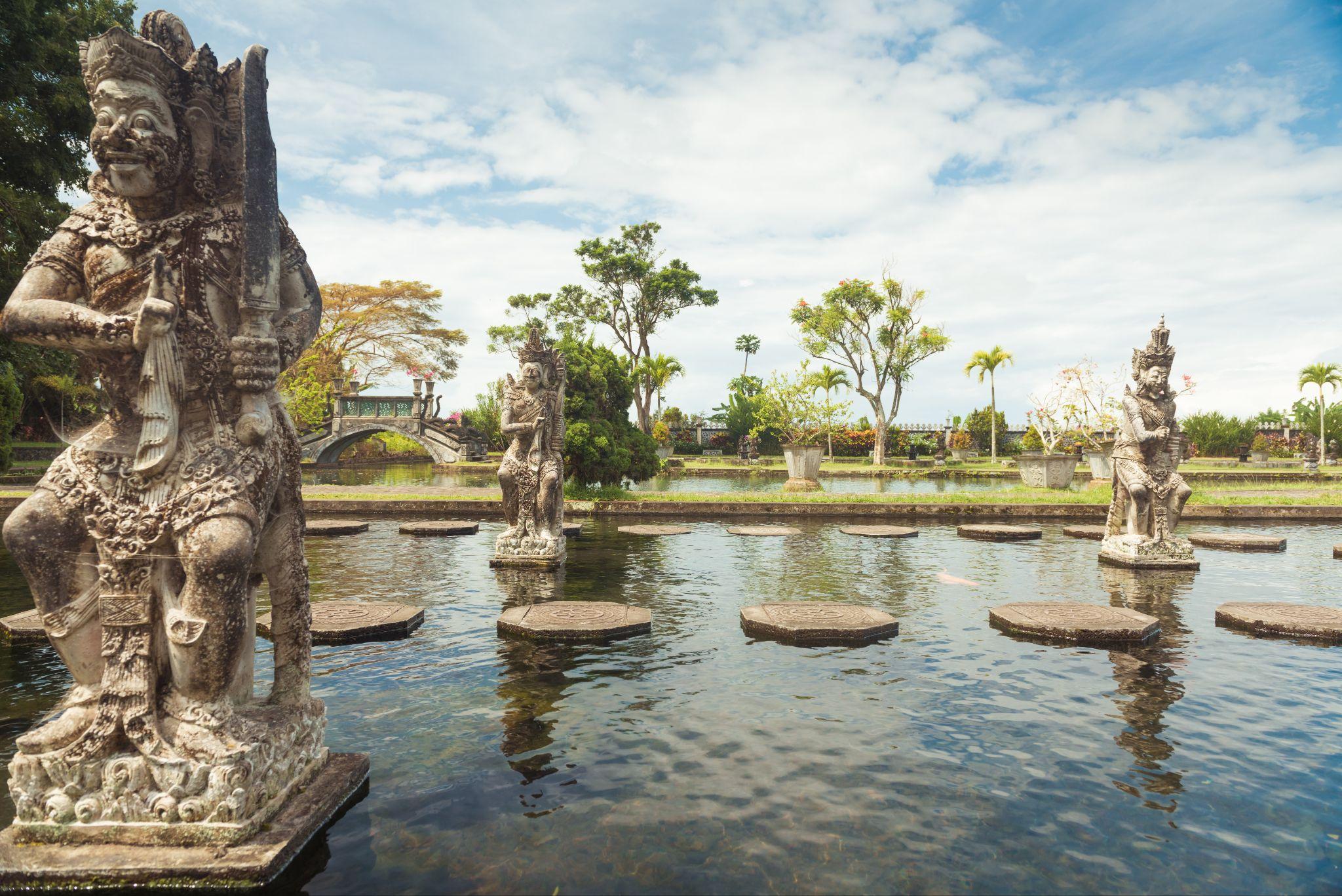 Carved stone guardian statues standing in a temple water garden