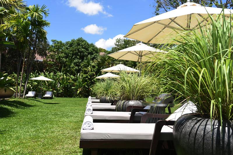 Sun loungers and parasols on the lawn in the tropical garden at Jaya House River Park