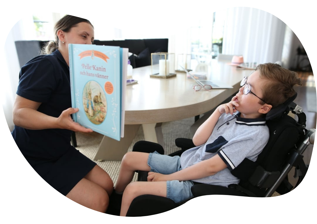 Personlig assistent som läser bok för ett barn med autism