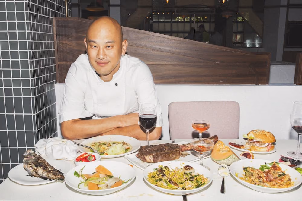 Chef Tim Ma seating on a table with food and drinks