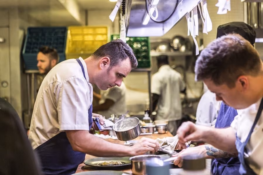 group of cooks puting garnish at kitchen's plating station