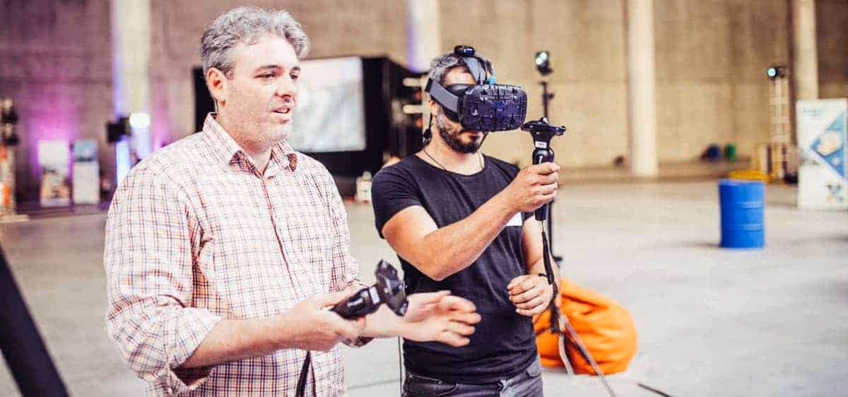 a man holding a device with another man in the background